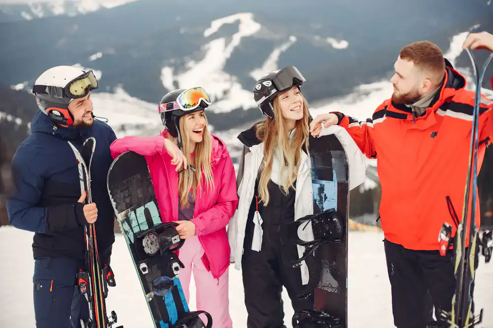 A group of friends laughing while preparing their ski gear in the morning