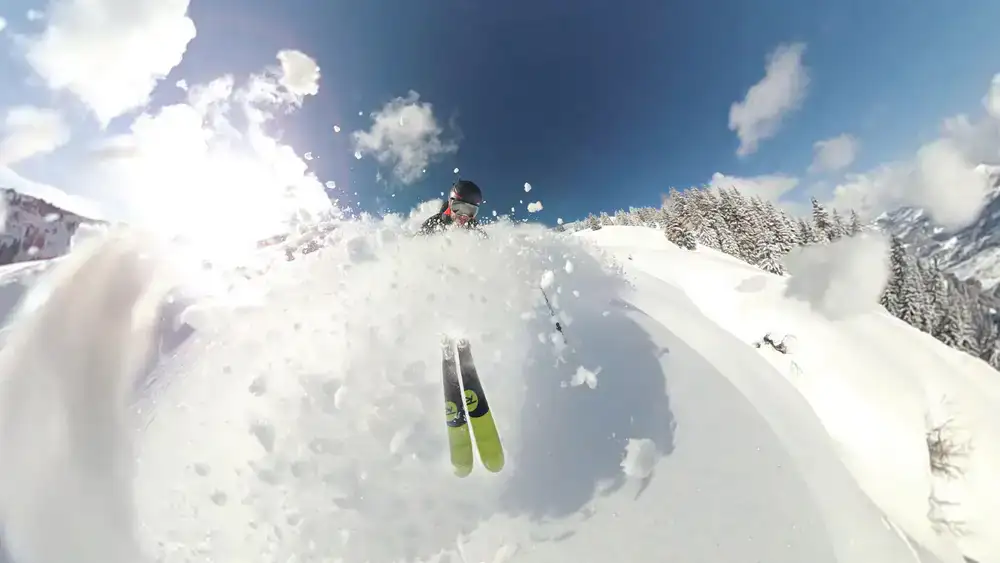 Skier carving through fresh powder on a sunny day