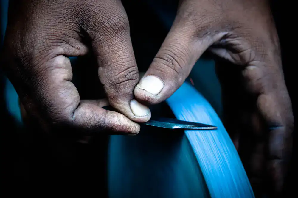 Technician carefully sharpening the metal edges of a snowboard in the workshop